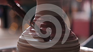 Female potter paints on rotating clay pot on the pottery wheel. Close up shot of potter making ceramic pot on pottery