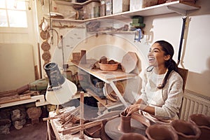 Female Potter Shaping Clay For Pot On Pottery Wheel In Ceramics Studio