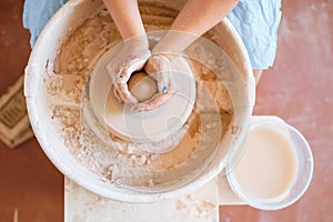 Female potter shaping a pot on pottery wheel