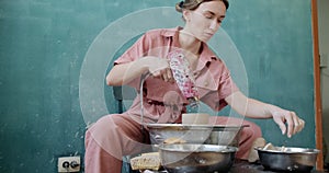 Female potter sitting and firing a shape cup clay on the pottery wheel. Woman making ceramic item. Pottery firing