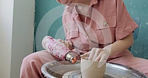 Female potter sitting and firing a shape cup clay on the pottery wheel. Woman making ceramic item. Pottery firing