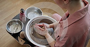 Female potter sitting and makes a cup on the pottery wheel. Woman making ceramic item. Pottery working, handmade and