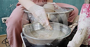 Female potter sitting and makes a cup on the pottery wheel. Woman making ceramic item. Pottery working, handmade and