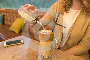 Close up of female putting sugar in her coffee in cafe