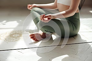 Female practicing padmasana in lotus position at home