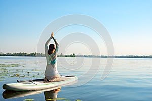 Female practicing yoga on a SUP board