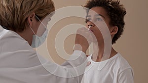 Female practitioner doctor takes nose swab of small patient