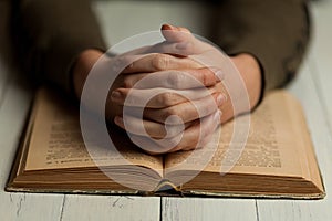 Female praying hands on an open bible