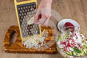 Female prepares a fresh vegetable salad. Close-up grates celery root on an iron grater for making fresh vegetable salad. Delicious