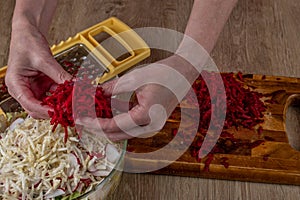 Female prepares a fresh vegetable salad. Close-up grates red beets on an iron grater for making fresh vegetable salad. Delicious