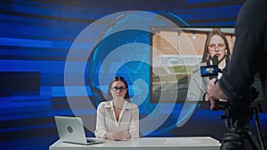 Female presenter in the studio. Woman news host sits at desk presenting daily events, talking on air with reporter