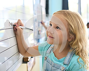 Female Primary Or Elementary School Student Writing On Whiteboard In Classroom Lesson