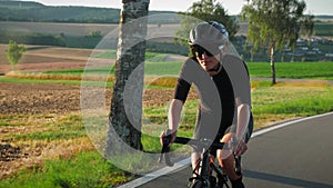 Female pro cyclist hard pedaling on road bike at sunset. Woman athlete training on bicycle, preparing for competition race. Profes