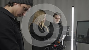 Female producer, camera operator, lighting technician in the studio during filming. The cameraman adjusts the camera