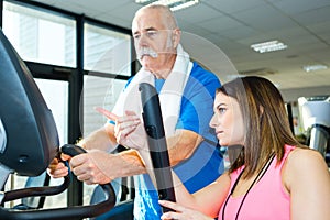 Female professional fitness trainer helping elderly client