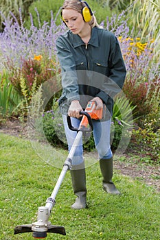 female professional gardener using strimmer