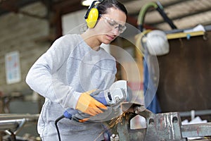 female professional master standing with circular saw in workplace