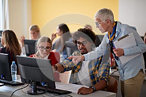 Female professor checking students work at an informatics lecture