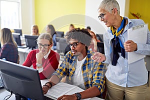 A female professor checking work of students at the informatics lecture. Smart young people study at the college. Education,