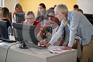 Female professor correcting students errors at an informatics lecture photo