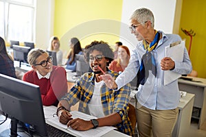 A female professor giving help to students at the informatics lecture. Smart young people study at the college. Education, college