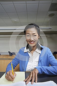 Female Professor Jotting Down Notes On Paper photo