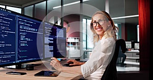 Female Programmer Coding On Multiple Computer Screens