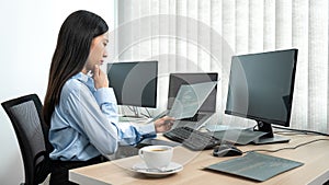 Female programmer reading document of database code to thinking for website development while using multiple