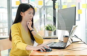 Female programmer are using laptop to create programs for clients.She put hand on the mouse and and face was serious