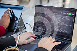 Female programmer writes some code and drinks coffee while sitting near her colleague