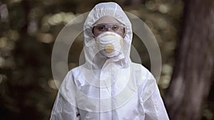 Female in protective mask looking camera, exclusion area research, biohazard photo