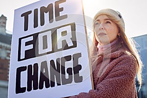 Female Protestor On Demonstration March Holding Time For Change Placard