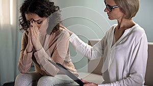 Female psychologist comforting depressed young lady patient, mental health photo