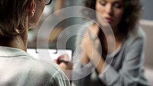 Female psychologist listening to young lady during personal session, depression