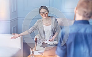 Female psychologist pointing on sofa while talking to child patient