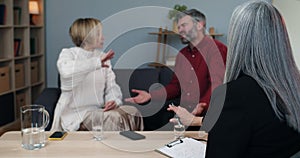 Female psychologist trying to calm down married couple that discussing family problems and shouting on each other while