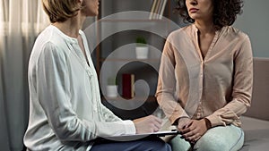 Female psychotherapist listening to young lady at therapy session, consultation