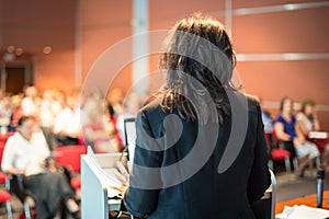 Female public speaker giving talk at Business Event.