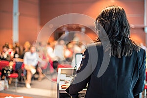 Female public speaker giving talk at Business Event.