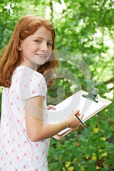 Female Pupil Making Notes On School Nature Field Trip