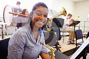 Female Pupil Playing Saxophone In High School Orchestra