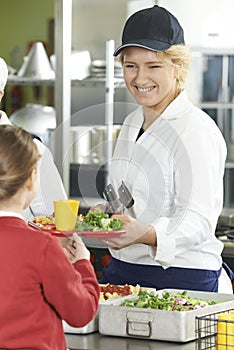 Female Pupil In School Cafeteria Being Served Lunch By Dinner La