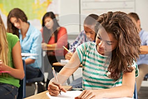 Female Pupil Studying At Desk In Classroom