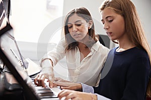 Female Pupil With Teacher Playing Piano In Music Lesson