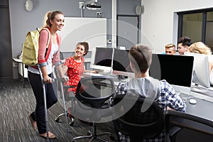 Female Pupil Walking On Crutches In Computer Class