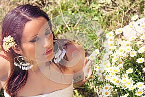 Female purity. Beautiful woman with daisies on the lawn. Closed eyes