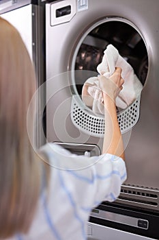 Rear view on woman putting dirty laundry into washing machine indoors, closeup