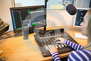 Female radio host in front of screen operating sound mixer