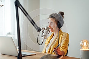 Female radio host streaming podcast using microphone and laptop at his home studio
