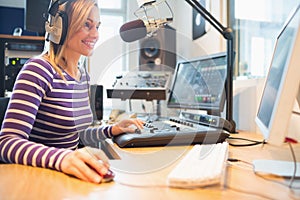 Female radio host using computer while broadcasting